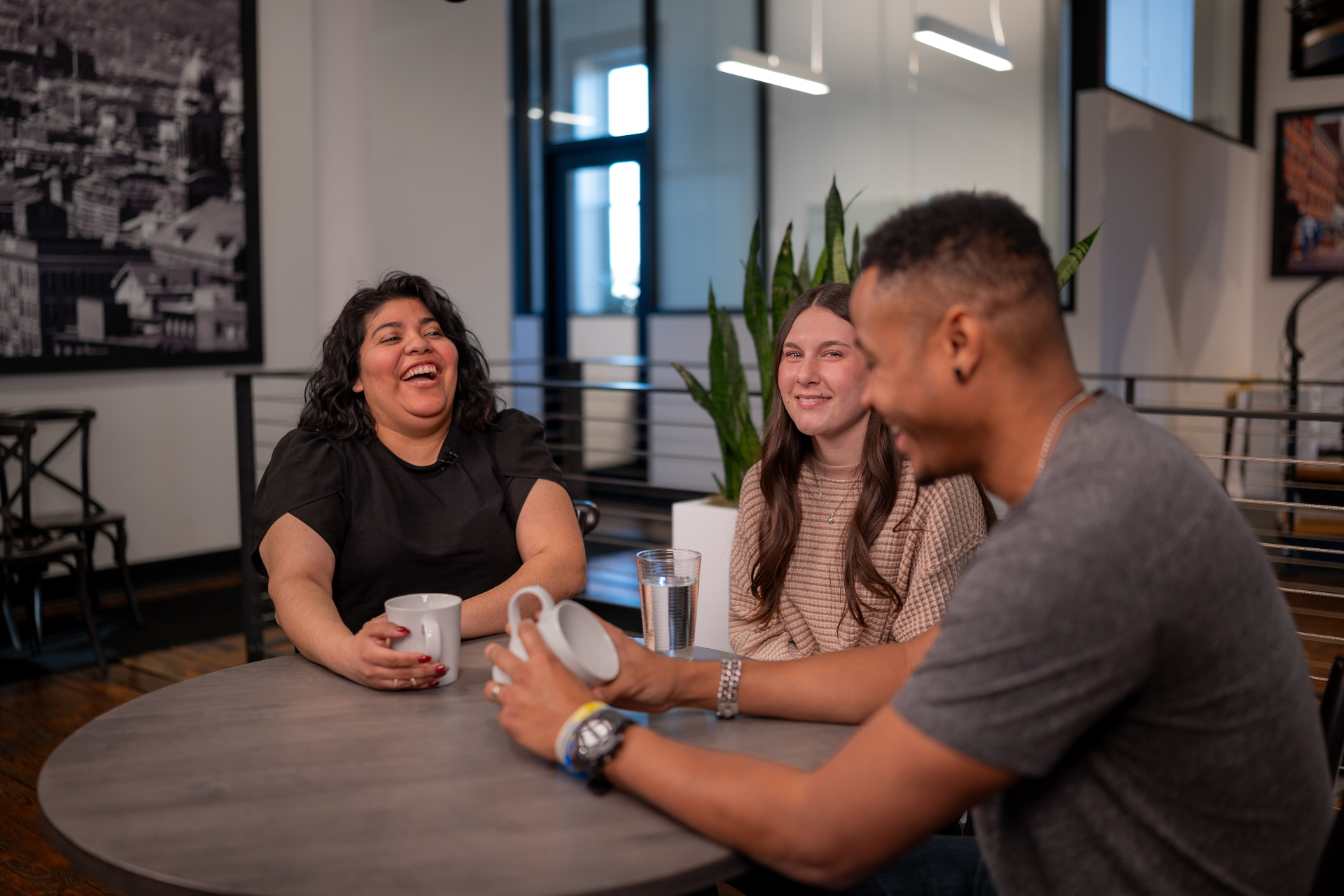 Three people talking together around a table in a triad practice group
